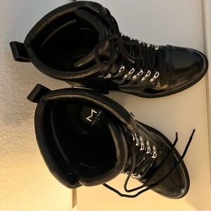 Black combat boots, shiny, rounded toe, lace up closure.